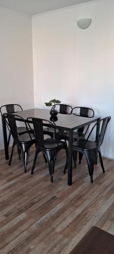 una mesa de comedor negra y sillas con una planta en Departamento cerca de Av. del Mar La Serena, en La Serena