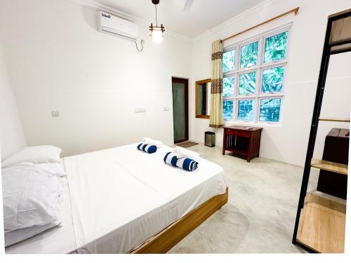 a white bedroom with a bed and a window at Ithaa Hiya Dhihfushi in Dhiffushi