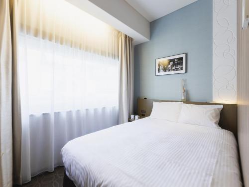 a bedroom with a white bed and a window at Hotel Gracery Ginza in Tokyo
