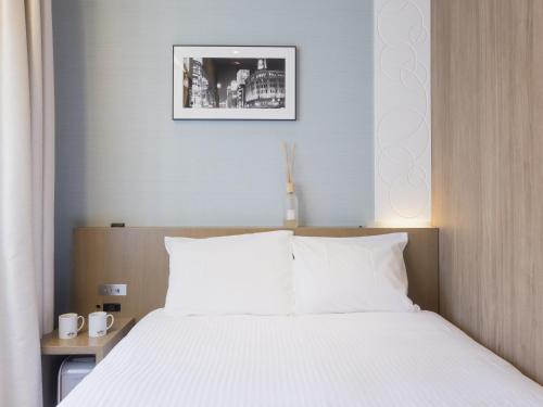 a bedroom with a large bed with white sheets at Hotel Gracery Ginza in Tokyo