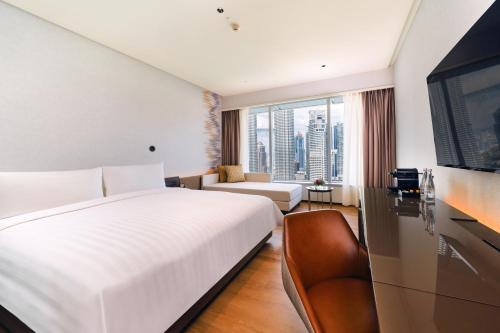 een slaapkamer met een groot wit bed en een bank bij Traders Hotel, Kuala Lumpur in Kuala Lumpur