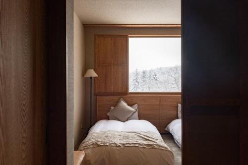 a small bedroom with a bed and a window at Asahidake Yumoto Yukomanso in Higashikawa