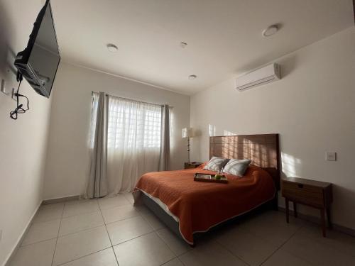 una camera da letto con un letto con lenzuola arancioni e una finestra di Departamentos DOS21 a Mazatlán