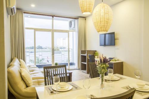 a dining room with a table and a living room at Asiban Quay Boutique Hotel in Phnom Penh