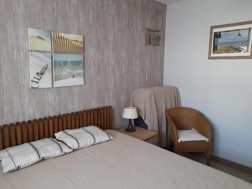 - une chambre avec un lit, une chaise et des photos dans l'établissement Maison T3 avec cour, à deux pas du port de l'Aiguillon, proche commodités et plage - Arcachon - FR-1-319-126, à Arcachon