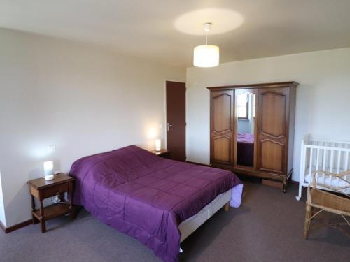 Schlafzimmer mit einem lila Bett und einem Holzschrank in der Unterkunft Gîte Montboudif, 3 pièces, 4 personnes - FR-1-742-59 