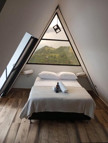 a bed in a room with a large window at De las flores Glamping Alpino in Jardin