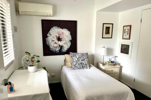 1 dormitorio con 2 camas y una pintura floral en la pared en Swan Guest House, en Brisbane