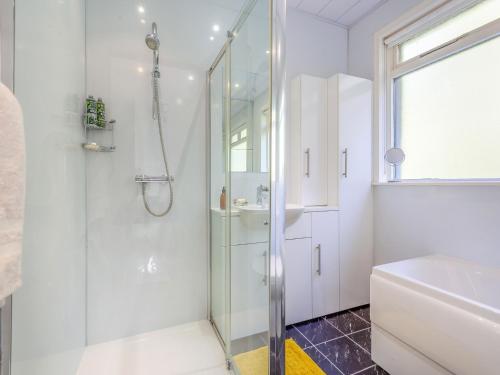 uma casa de banho branca com um chuveiro e um lavatório. em Cathel Sheiling em Thurso