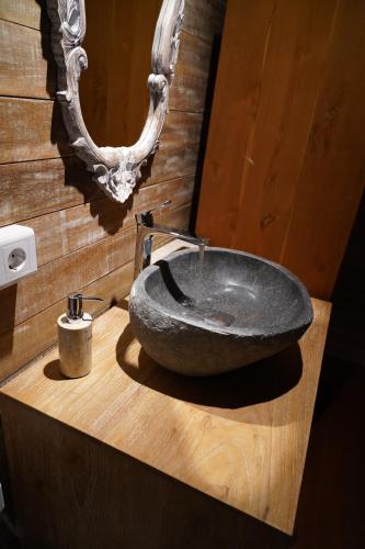 a bathroom with a stone sink on a wooden counter at Lastana Suite Joglo Ubud in Ubud