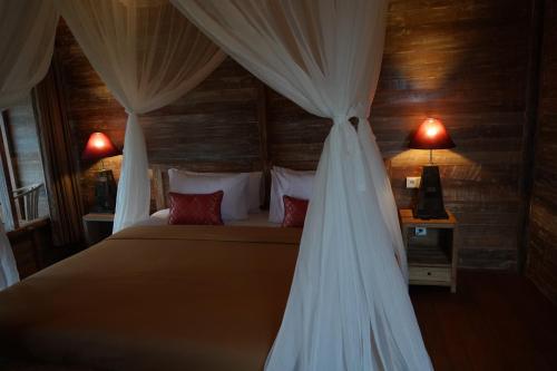 a bedroom with a bed with a canopy and two lamps at Lastana Suite Joglo Ubud in Ubud