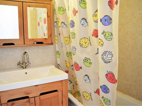 La salle de bains est pourvue d'un lavabo et d'un rideau de douche avec des poissons. dans l'établissement Appartement Duplex avec Terrasse, 2 Chambres, Parking Privé à 2 Min de la Plage - FR-1-251-569, au Lavandou