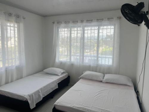 two beds in a room with white walls and windows at Jerusalén in Mariquita