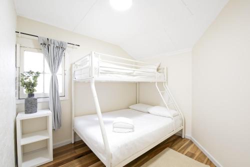 a white bunk bed in a room with a window at A Quaint Darlinghurst Cottage in Sydney