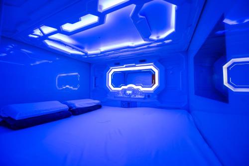 a blue room with a bed and a window at Space Q Capsule Hotel in Sydney