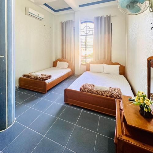 een slaapkamer met 2 bedden, een bureau en een raam bij HOÀNG HẢO HOTEL in Pleiku