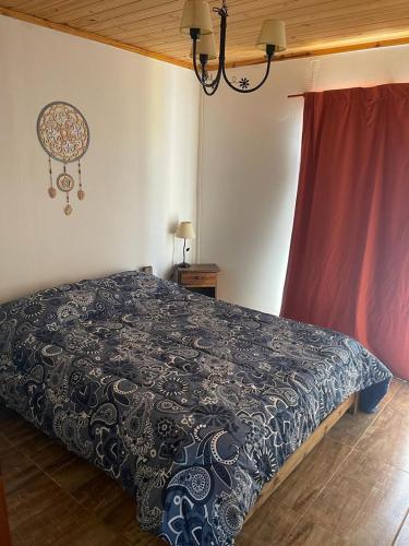 1 dormitorio con 1 cama con edredón blanco y negro en CABAÑA EN CALAMUCHITA CORDOBA en Villa Ciudad Parque