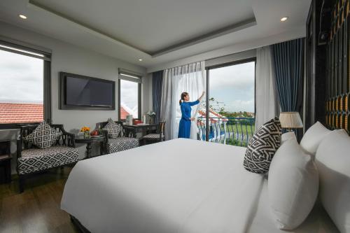 a woman standing on a balcony in a hotel room at Serene Nature Hotel & Spa in Hoi An