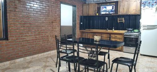 a kitchen with a black table and chairs and a brick wall at Paz alojamiento in Jardín América