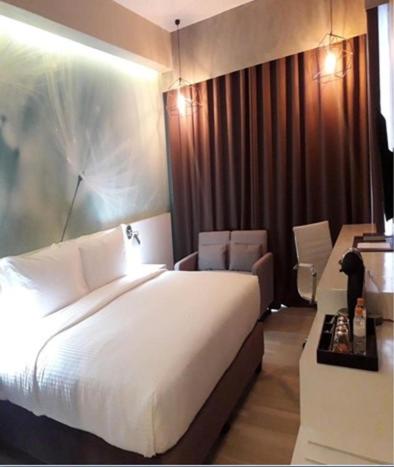 a bedroom with a large white bed and a desk at MAXX HOTEL MAKATI by MAXIHOME LAND in Manila