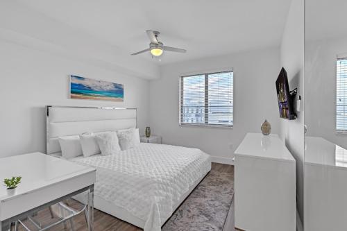 a white bedroom with a bed and a ceiling fan at Modern 2 Bed in the Heart of Doral Free Parking in Hialeah Gardens