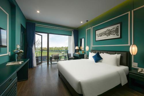 a bedroom with a large white bed and a balcony at Serene Nature Hotel & Spa in Hoi An