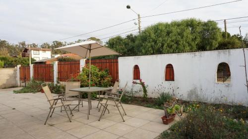 a patio with a table and chairs and an umbrella at Acogedora casa en Algarrobo in San Antonio