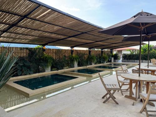 a swimming pool with an umbrella and tables and chairs at Finca del Café - Casa Bourbon in Santa Rosa de Cabal