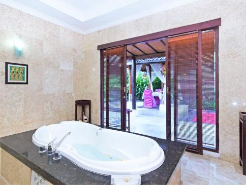 One Bedroom Private Villa Kuta في سمينياك: حمام مع حوض كبير في الغرفة