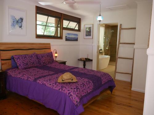 Un dormitorio con una cama morada con un sombrero. en Fairy Falls - romantic Daintree Rainforest retreat with enchanting waterfall en Cow Bay