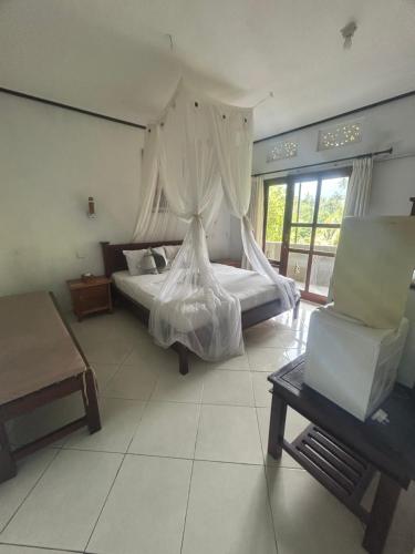 a bedroom with a bed and a chair at Sugi Gede Homestay in Singaraja