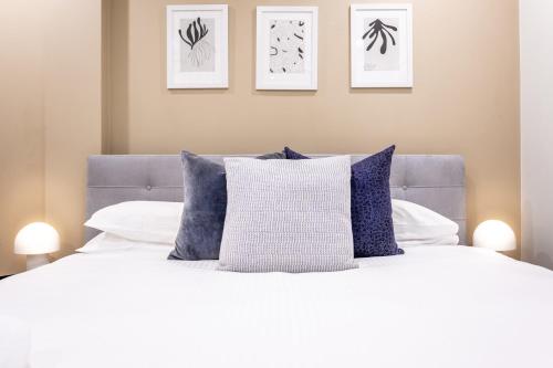 un letto con cuscini bianchi e blu e quadri appesi al muro di Light Resort Style Haven in Darling Harbour a Sydney