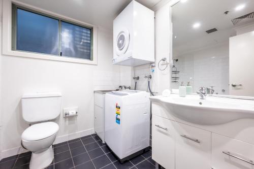bagno bianco con servizi igienici e lavandino di Light Resort Style Haven in Darling Harbour a Sydney