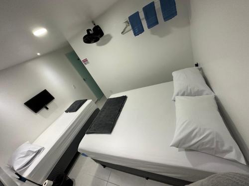 een kleine kamer met een bed met witte lakens bij Quarto privativo com banheiro compartilhado em Pousada recém construída,a 500mts do pátio do forró in Caruaru
