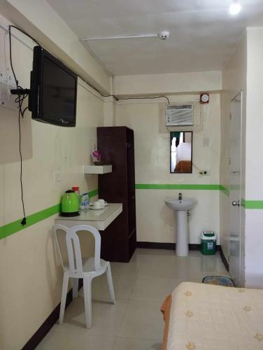 Habitación pequeña con lavabo y TV en la pared. en jazmine hotel, en San José