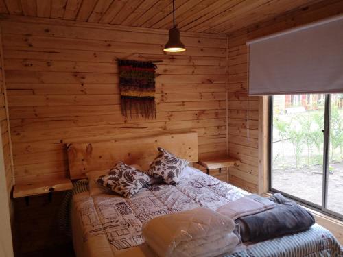 a bedroom with a bed in a log cabin at Rukawe Quillon in Quillón