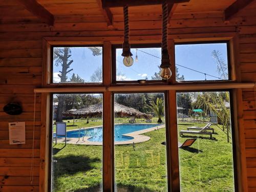 a window in a cabin looking out at a swimming pool at Rukawe Quillon in Quillón