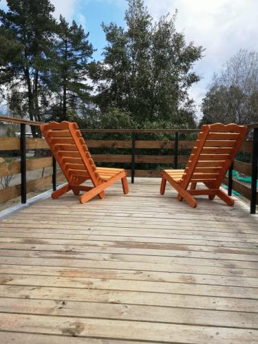 two wooden chairs sitting on top of a wooden deck at Rukawe Quillon in Quillón