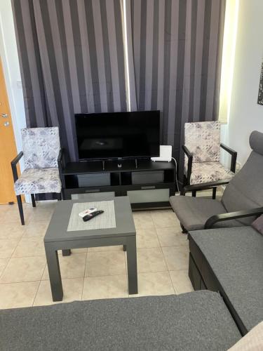 ein Wohnzimmer mit einem TV, 2 Stühlen und einem Tisch in der Unterkunft Protaras, Janas apartment in Protaras