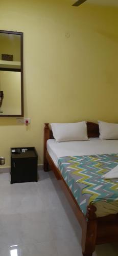 a bedroom with a bed and a mirror on the wall at Varadhar Guest House in Kanchipuram
