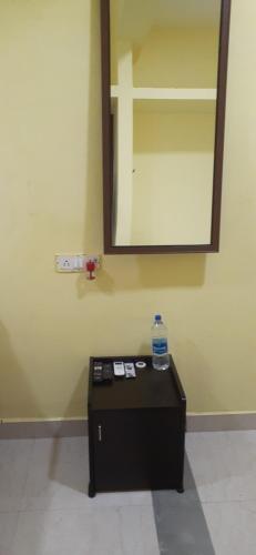 a mirror on a wall with a table in a room at Varadhar Guest House in Kanchipuram