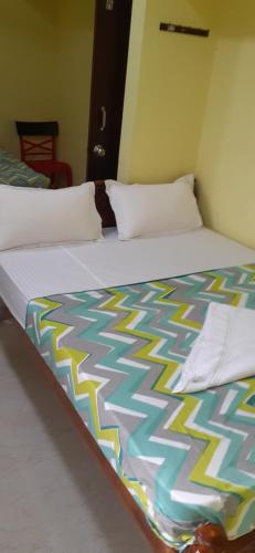 a bed with a colorful blanket on top of it at Varadhar Guest House in Kanchipuram