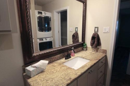 La salle de bains est pourvue d'un lavabo et d'un miroir. dans l'établissement Cozy Aggieland Vacay, à Bryan