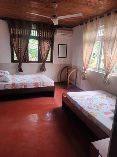 two beds in a room with two windows at Lovely FLowers in Mount Lavinia in Mount Lavinia