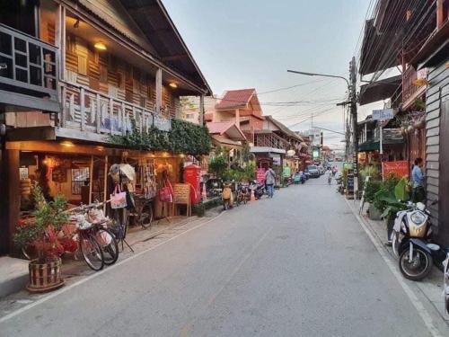 a street in an asian town with shops and motorcycles at Granny One Guest House in Chiang Khan