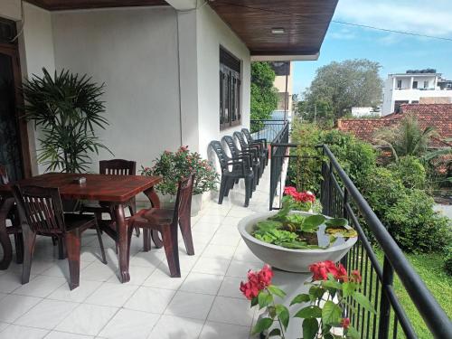 a porch with a wooden table and chairs on a balcony at Lovely FLowers in Mount Lavinia in Mount Lavinia