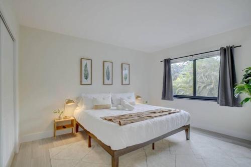 a white bedroom with a bed and a window at 2BR Cozy FLL Retreat! in Fort Lauderdale