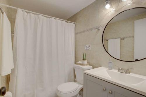 a bathroom with a toilet and a sink and a mirror at 2BR Cozy FLL Retreat! in Fort Lauderdale
