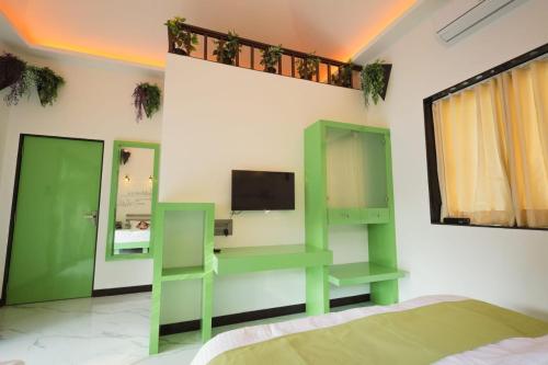 a bedroom with green shelves and a tv on a wall at Cherryleen Resort Nagaon Alibaug in Nagaon