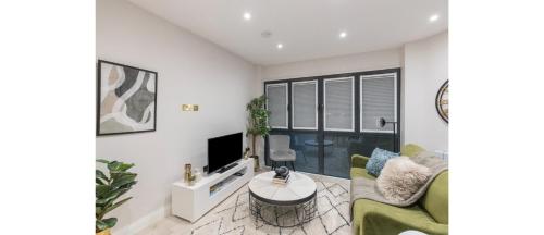a living room with a couch and a tv at Luxe Minimalist 1-Bed Flat : 7 Mins from Station in London